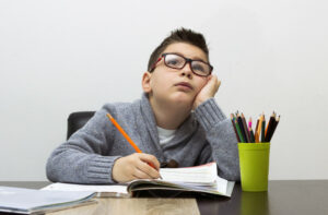 menino-jovem-frustrado-lição-de-casa-escrevendo-menino-estudando-mesa-criança-desenho-com-lápis
